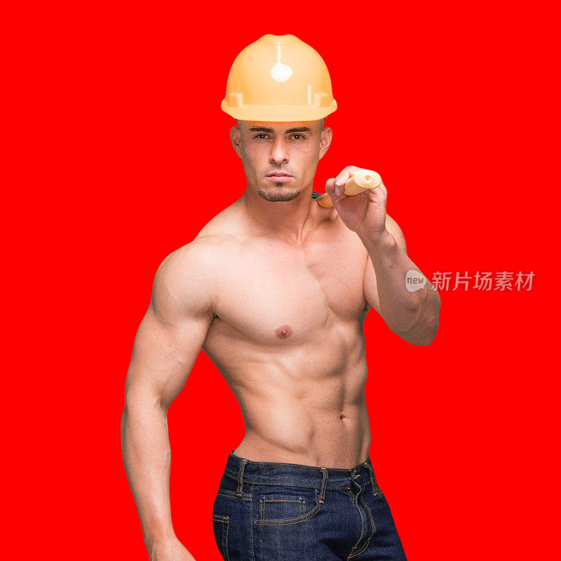 一个人/腰部以上/正面拉丁美洲和西班牙裔男性/年轻男性建筑工人前面的有色背景，穿着牛仔裤/裤子/头盔/工作头盔/安全帽，手持大锤/锤子/工作工具